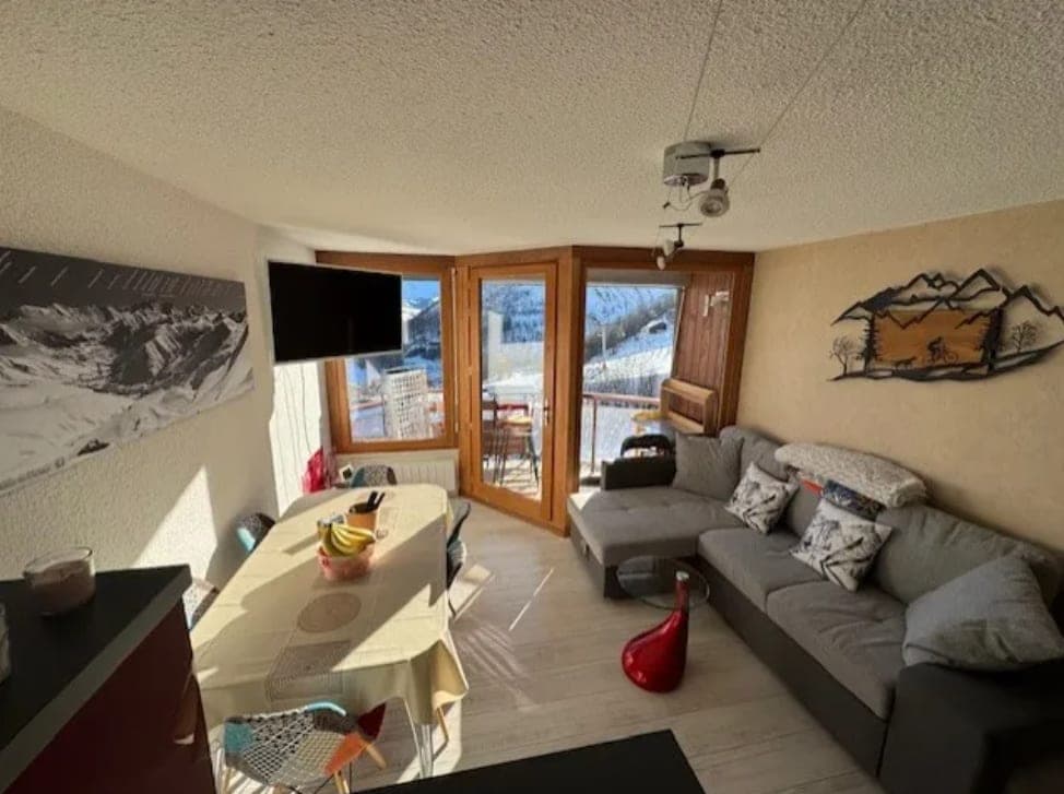 Séjour baigné de soleil, canapé d'angle et baie vitrée sur le balcon